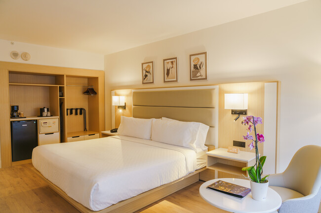 a bed with a white cover and a table with flowers